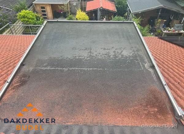 Verouderd plat dak met slijtage tussen schuine daken in Budel Verouderd plat dak met slijtage tussen schuine daken in Budel